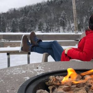 woman in ice skates sitting by a bonfire at Chateau Morritt in Mont Tremblant