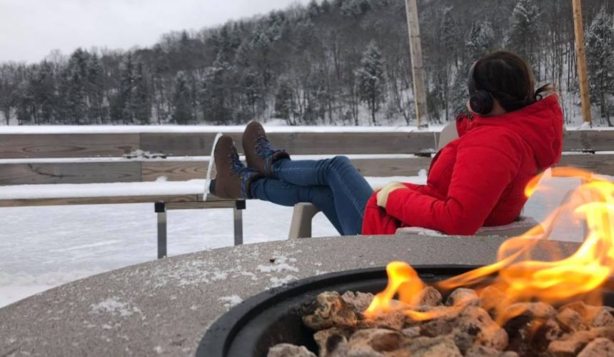 woman in ice skates sitting by a bonfire at Chateau Morritt in Mont Tremblant